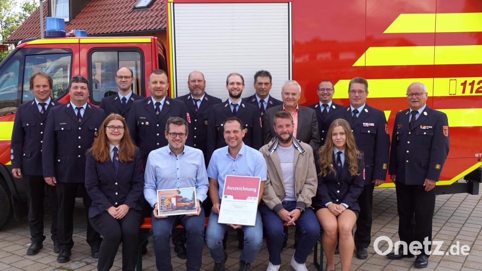 Zwei junge Damen der Wehr rahmten Michael Koch, Stefan Eulefeld und Tobias Müller (sitzend, Zweiter bis Vierter von links) bei der Übergabe ein. Dahinter stehend von rechts Kreisbrandinspektor Otte Braunreuther, Kreisbrandrat Stefan Gleißner, Kreisbrandmeister Florian Braunreuther und Bürgermeister Günter Kopp. Bild: bkr