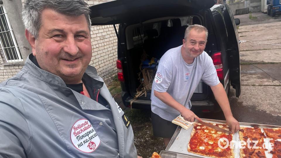Bäckermeister Reiner Dielt und Andreas Lehner beim Schneiden von Pizza. Bild: Dietl/exb