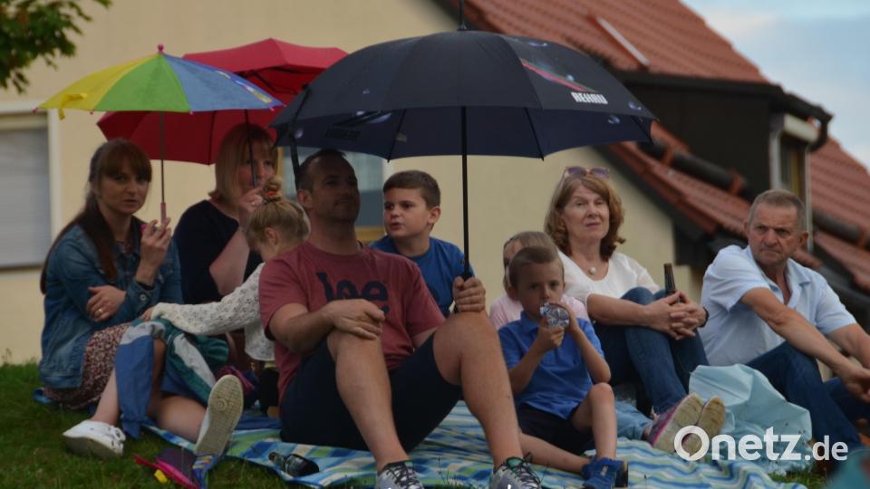 Die Zuhörer spannen ihre Regenschirme auf und bleiben beharrlich sitzen, um der Blasmusik zu lauschen. Bild: dob