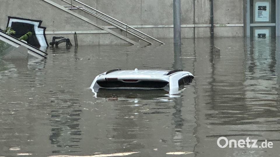 Ein Auto, von dem man nur das Dach erkennen kann, steht in einer überschwemmten Straße an einer Unterführung nach einem Unwetter. Bild: NEWS5/dpa