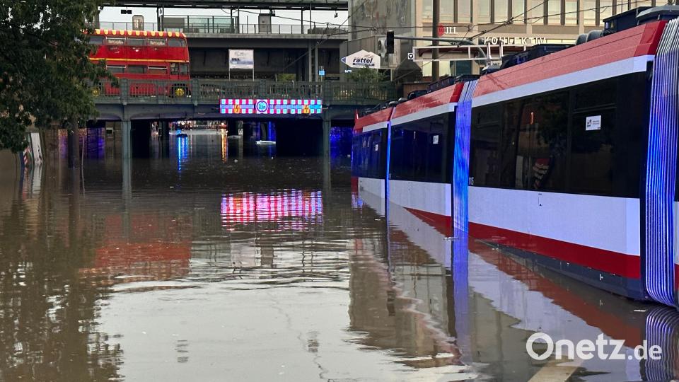 Eine Straßenbahn steht in einer überschwemmten Straße an einer Unterführung nach einem Unwetter. Bild: NEWS5/dpa