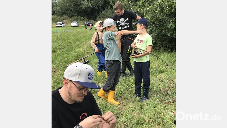 Vorsitzender Tobias Christau (im Vordergrund) hilft den Kindern beim Befestigen eines Wurms am Angelhaken. Bild: mma