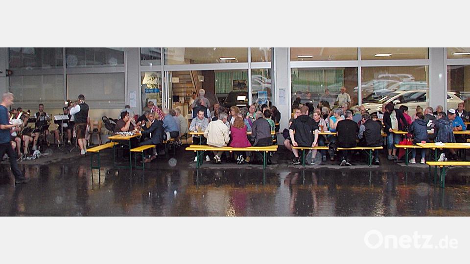 Unter dem Vordach des Autohauses gab es für alle Schutz vor Regen. Hier fand auch die Blaskapelle einen trockenen Platz. Bild: ld