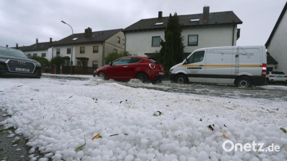 Hagel liegt auf einem Gehsteig und treibt auf einer überfluteten Straße. Gewitter mit starkem Wind und Hagel haben am Samstagnachmittag für zahlreiche Einsätze in Schwaben gesorgt. Bild: Karl-Josef Hildenbrand/dpa