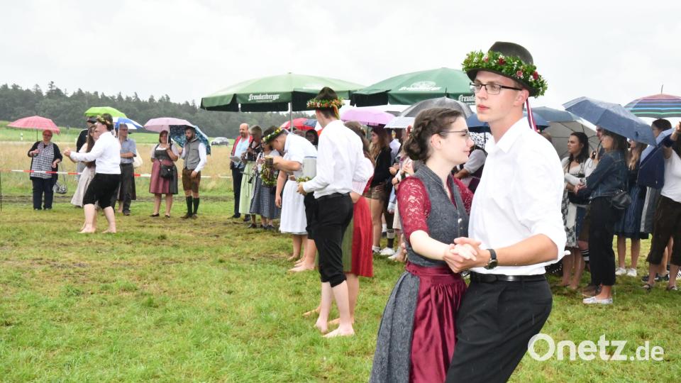 15 Paare trotzen bei der Aschacher Kirwa dem Regen und tanzen ohne Schuhe und Strümpfe um den Baum. Bild: sche