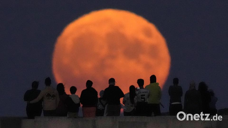 Der Vollmond erhebt sich über dem Lake Michigan, während Zuschauer vom Strand der 31st Street in Chicago aus zusehen. Bild: Charles Rex Arbogast