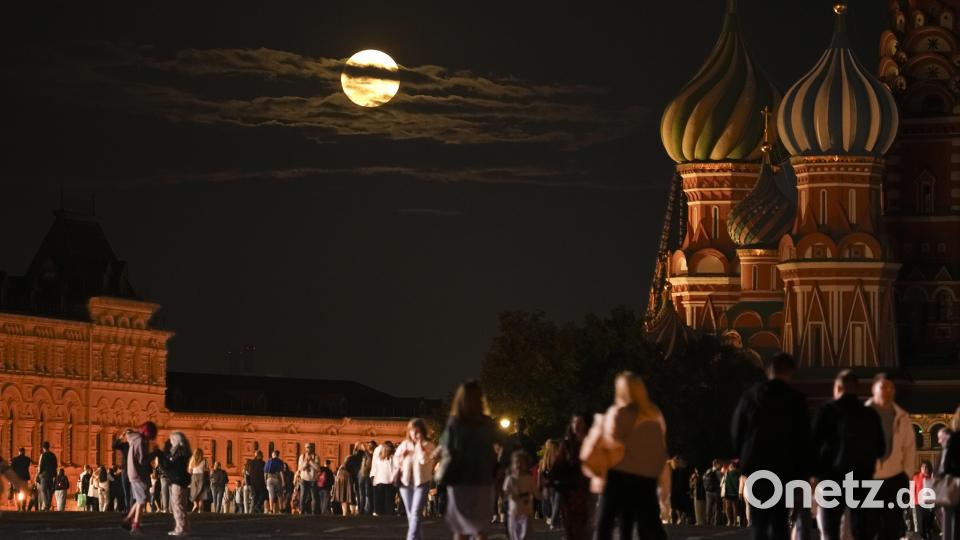 Der Supermond steht über einem historischen Gebäude und der Basilius-Kathedrale (r), während Menschen auf dem Roten Platz spazieren gehen. Bild: Alexander Zemlianichenko
