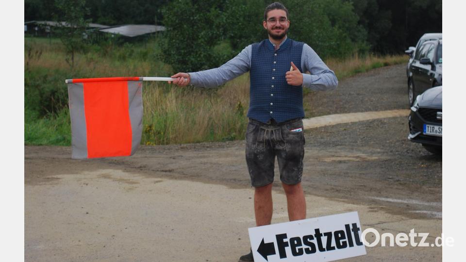 Der Einweiser weist den Autos und Bussen am Vormittag den Weg zum Parkplatz beziehungsweise Festzelt. Bild: tss