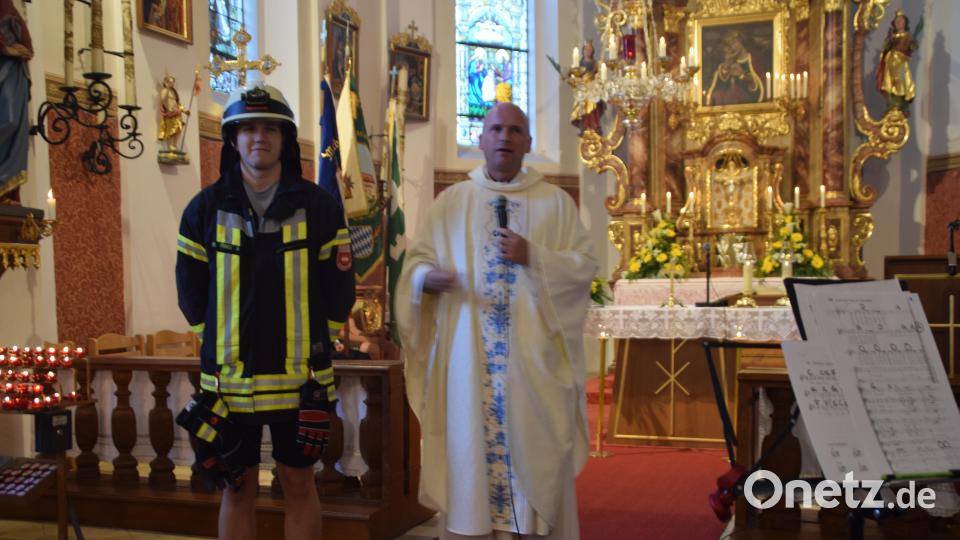 Symbolisch steckte Pfarrer Andreas Ring einen Jugendlichen in eine Feuerwehrjacke. Um aufzuzeigen, dass so wie die Feuerwehr Leben rettet, auch Jesus unser Leben gerettet hat. Bild: swo