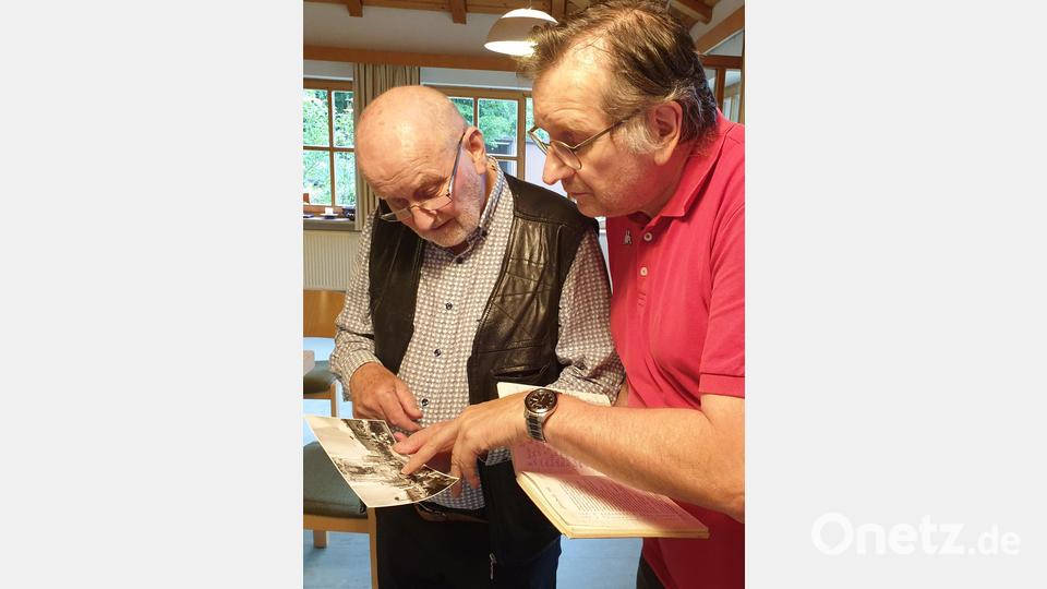 Chorleiter Günter Weigl (rechts) und Bläser Richard Keßler und beugen sich über die Chronik, in der die hundertjährige Geschichte festgehalten ist. Bild: Susanne Götte/exb
