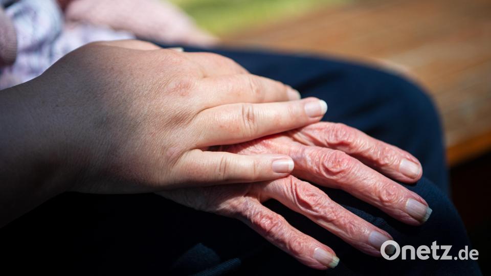 Die Hand einer Pflegefachkraft liegt auf der Hand einer Bewohnerin des Seniorenheims. Symbolbild: Sina Schuldt/dpa