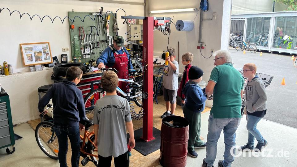 Ewald Oppl (in roter Latzhose) erklärte den Kindern einfache Reparaturen am Fahrrad. Bild: Dominik Göhl/exb