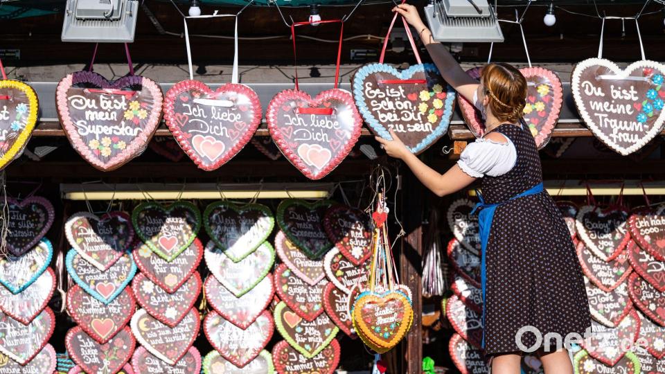 Eine Schaustellerin hängt ein Lebkuchenherz auf. Bild: Lukas Barth/dpa