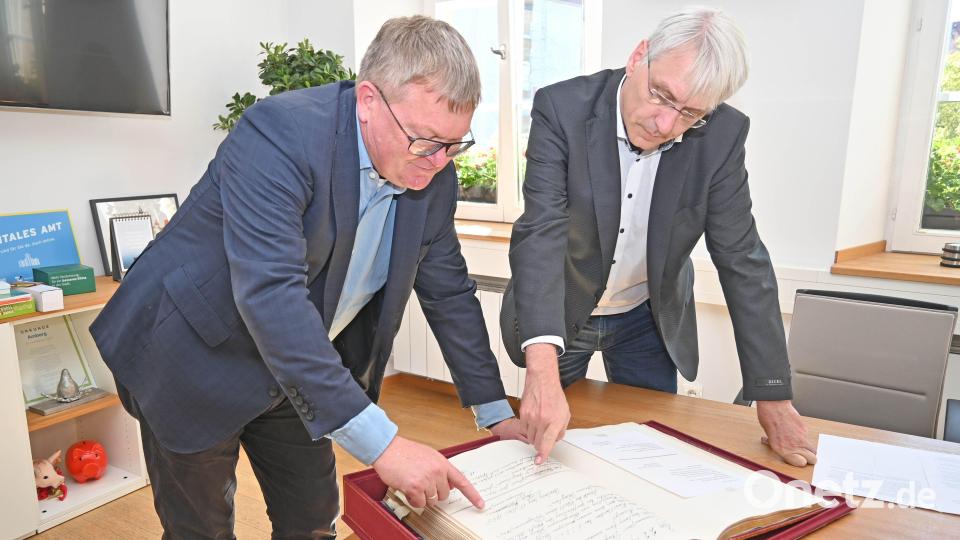 Oberbürgermeister Michael Cerny (links) und Stadtarchivar Dr. Andreas Erb blättern im Goldenen Buch der Stadt, das heuer 100 Jahre alt wird. Bild: Thomas Graml, Stadt Amberg/exb