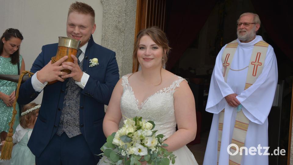Nach dem Gottesdienst musste das Brautpaar das gefüllte Burschenhorn leeren. Im Hintergrund Pfarrseelsorger Pater Benedikt Leitmayr. Bild: jr