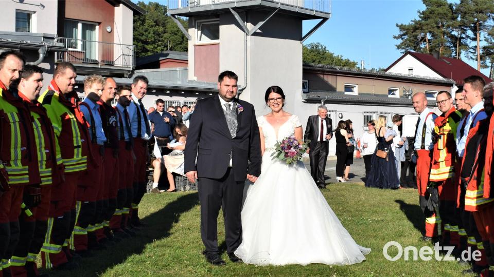 Markus und Ramona Gradl schreiten durch ein verspätetes Spalier der Feuerwehr-Kameraden. Dieses Mal tragen die Einsatzkräfte Krawatte und Schutzanzug, weil sie zu einem Einsatz ausrücken mussten. Bild: rgr