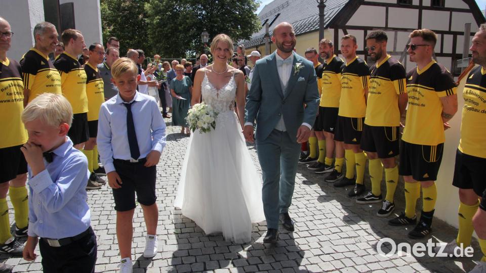 Das Brautpaar durchschreitet das Ehrenspalier des FC Tirschenreuth. Bild: kro