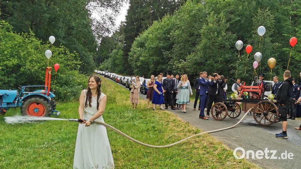 Die Braut beim „Aufhalten“ der Feuerwehr Heinersreuth. Hierbei musste mit der historischen Feuerwehrpumpe ein kleiner Brand gelöscht werden. Die Braut oblag die Bedienung des Strahlrohrs und Michael pumpte mit weiteren Helfern im Hintergrund das nötige Löschwasser Bild: hzi