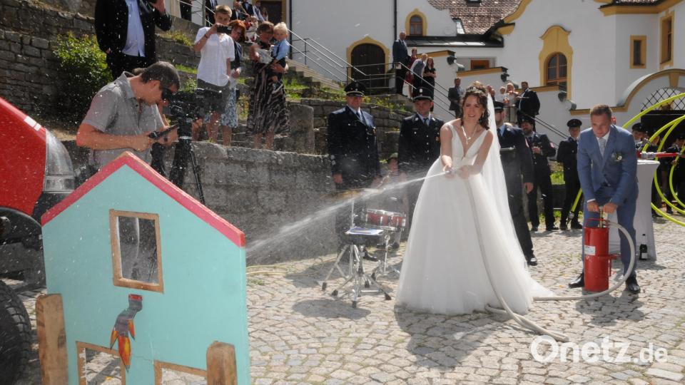 Den Umgang mit Wasserpumpe und Feuerwehrspritz beherrscht das Brautpaar perfekt. Bild: bey
