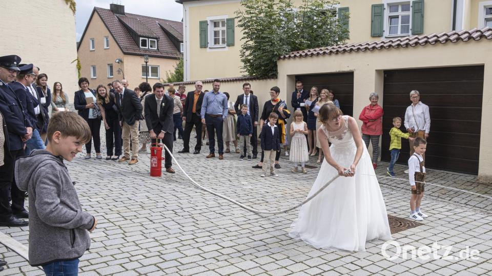 Corinna und Florian Wegmann mussten nach der Trauung ihre Geschicklichkeit beim „Löschangriff“ mit der kleinen Handspritze beweisen. Bild: fpoz