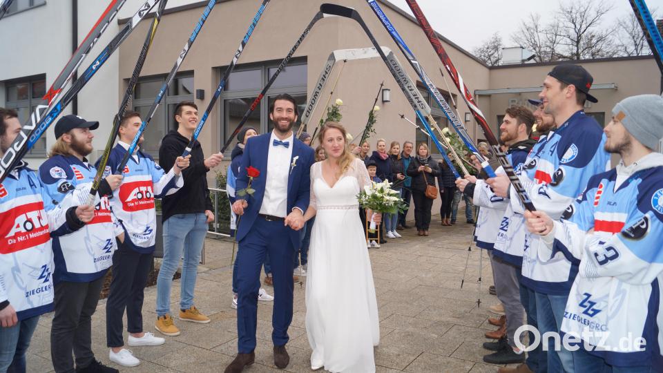Christian Wolf und seine Frau Mareike schreiten nach ihrer standesamtlichen Hochzeit vor Bürgermeister Ernst Lenk im Schirmitzer Bürgersaal durch ein langes Gratulationsspalier von Freunden und Bekannten sowie den Eishockey-Spielern des EV Weiden. Bild: du