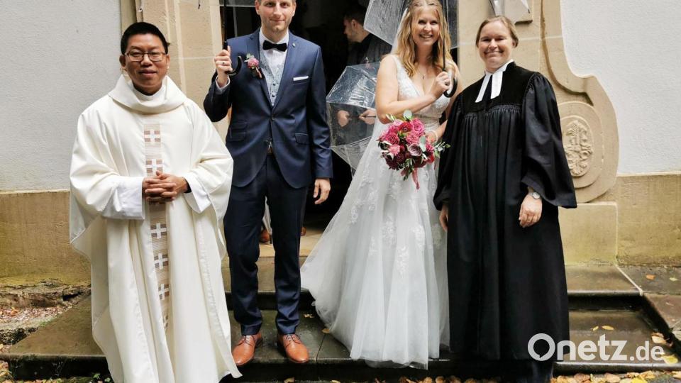 Das Brautpaar Vanessa und Christopher Schraml, eingerahmt von Pater Samuel Patton aus Creußen (links) und Pfarrerin Sabine Winkler aus Pegnitz (rechts), nach der Trauung am Kirchenportal der Heinersreuther Waldkapelle. Bild: hzi