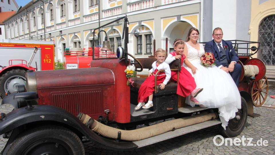 Melanie und Uwe Friedrich sowie die Blumenkinder Martha und Emma posieren auf einem Feuerwehr-Oldtimer. Bild: kro