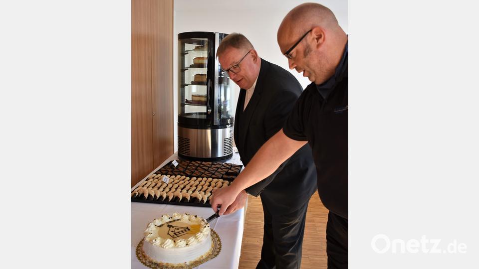 Pfarrer Thomas Berthold (links) und Tassilo Heimberg schneiden die Geburtstagstorte an. Bild: rgr
