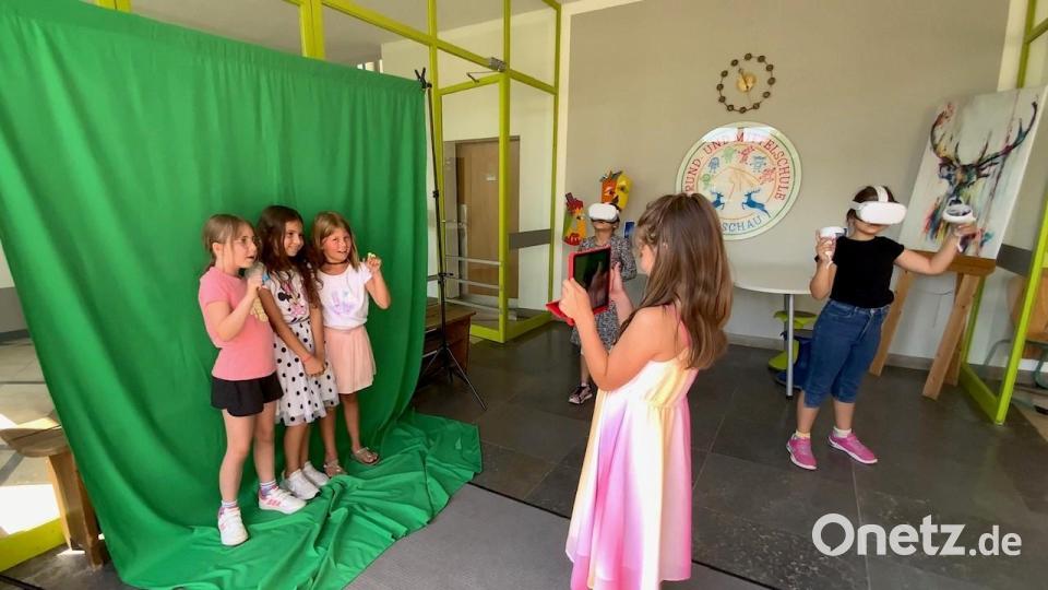 Zukunftsorientierter Unterricht an der Hirschauer Grundschule: Vier Kinder arbeiten am Greenscreen. Im Hintergrund tauchen zwei Mädchen mit ihren VR-Brillen in eine 3D-Welt ein. Sie lesen zum Beispiel mit einer Maus und müssen diese dabei durch eine märchenhafte Welt führen. Bild: u
