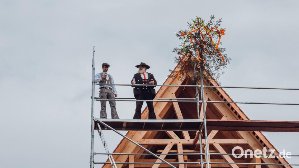 Zimmerermeister Armin Mannschott (recht) sprach den Richtspruch mit den abschließenden Worten „geweiht sei dieser Bau zur Stund“ hoch oben auf „Haus A“ der insgesamt vier Naturdorf-Häuser. Steinmetz Robert Mois assistierte. Bild: Susanne Forster