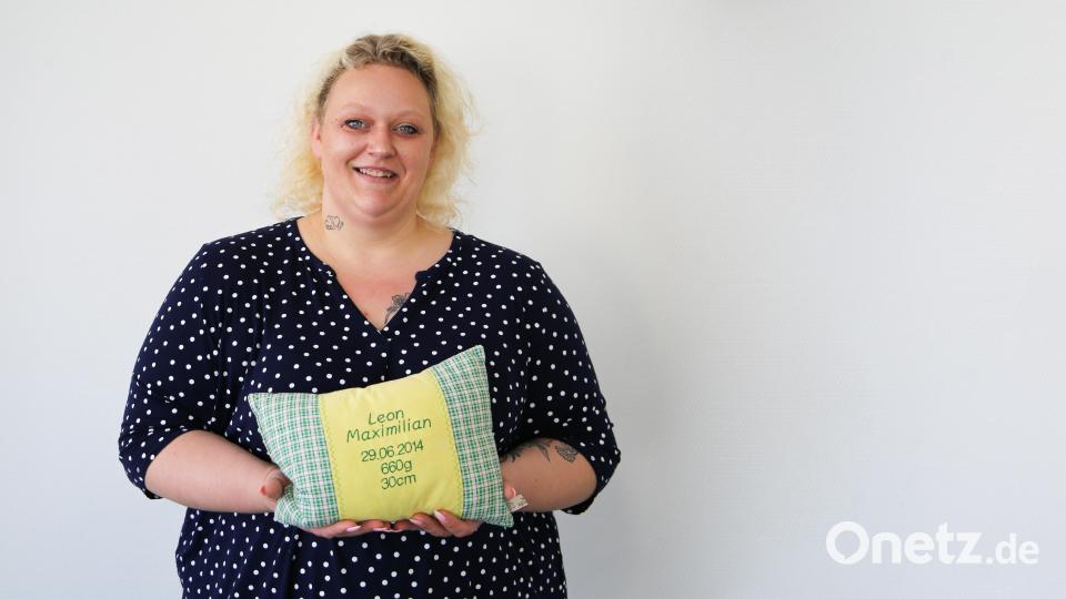 Stephanie Becher hält ein Kissen in der Hand, welches mit den Geburtsdaten ihres Sohnes Leon bestickt ist. Bild: Sebastian Böhm