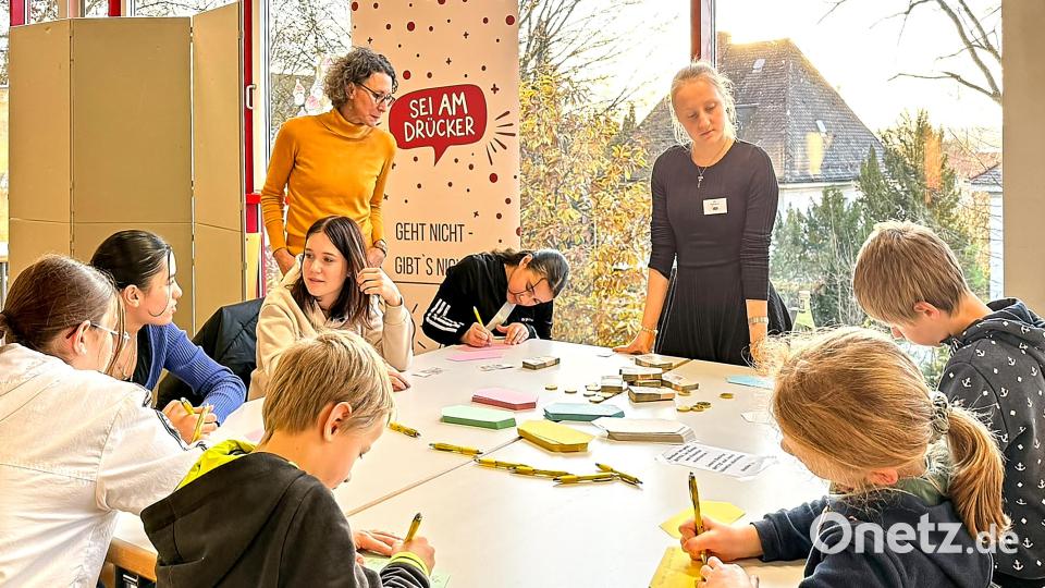 Kinder und Jugendliche am Formulieren von kreativen Ideen, beobachtet von Julia Schönhärl (Smart City Amberg) und Julia Regn (Moderatorin) in der Mensa des GMG. Bild: Peter Ringeisen