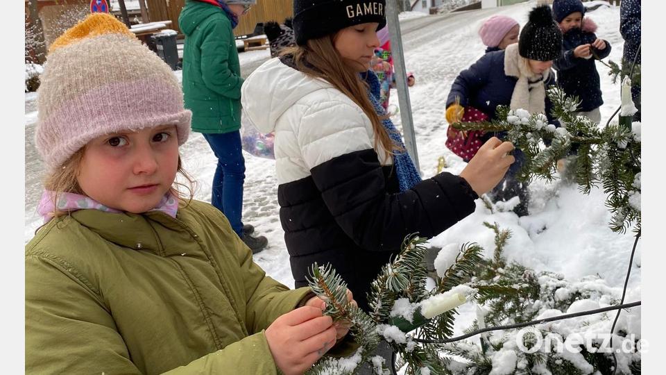 Die Kinder dekorieren unteren Äste des Kirchenthumbacher Christbaums mit ihren gebastelten Kunstwerken. Bild: Jugendforum/Tanja Groß/exb