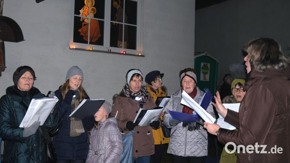 Der Singkreis postiert sich vor den geschmückten Häusern und erinnert musikalisch an die Geschichte der Herbergssuche. Bild: Hirsch