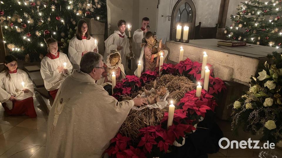 Pfarrer Hannes Lorenz legt in der Nabburger Pfarrkirche zu Beginn der feierlichen Christmette das Kind in die Krippe. Bild: aub