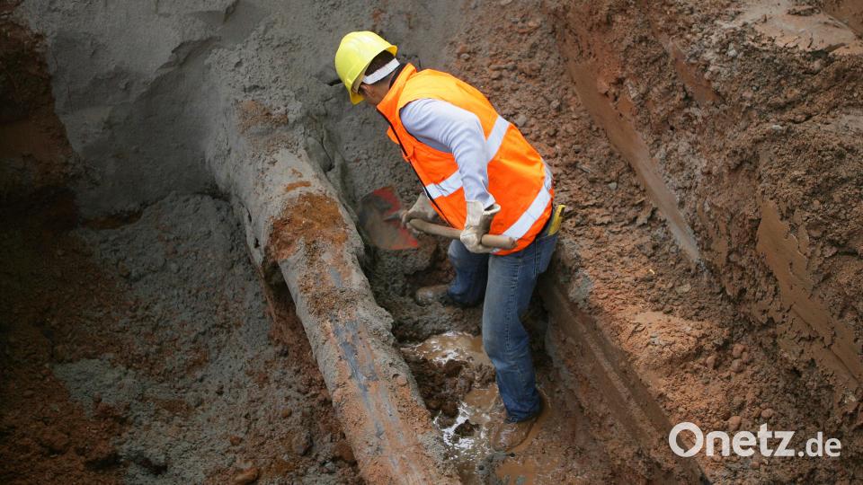 Ein Arbeiter schaufelt in einem Erdloch eine beschädigte Wasserleitung frei. Der Grund: Ein Wasserrohrbruch. Symbolbild: Uwe Anspach/dpa