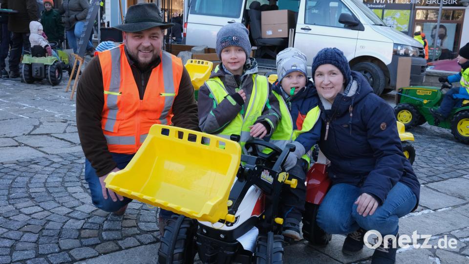 Stefanie Troidl (rechts) gewinnt mit ihren Söhnen Lukas und Simon einen Tretbulldog für den Kindergarten St. Martin in Neunburg vorm Wald, den ihnen Organisator Johannes Rester (links) überreicht. Bild: Hirsch