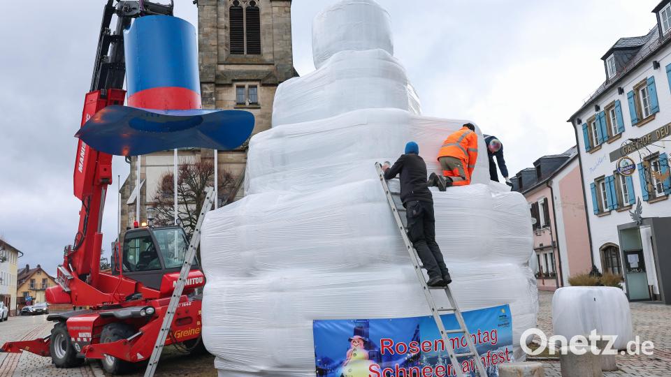 Der zwölf Meter hohe Schneemann «Jakob» steht für das Schneemannfest am Rosenmontag auf dem Marktplatz. Wegen Schneemangels verwendeten die freiwilligen Helfer dieses Mal weiße Heuballen. Der Kran bleibt aus Sicherheitsgründen stehen. Bild: Daniel Löb/dpa