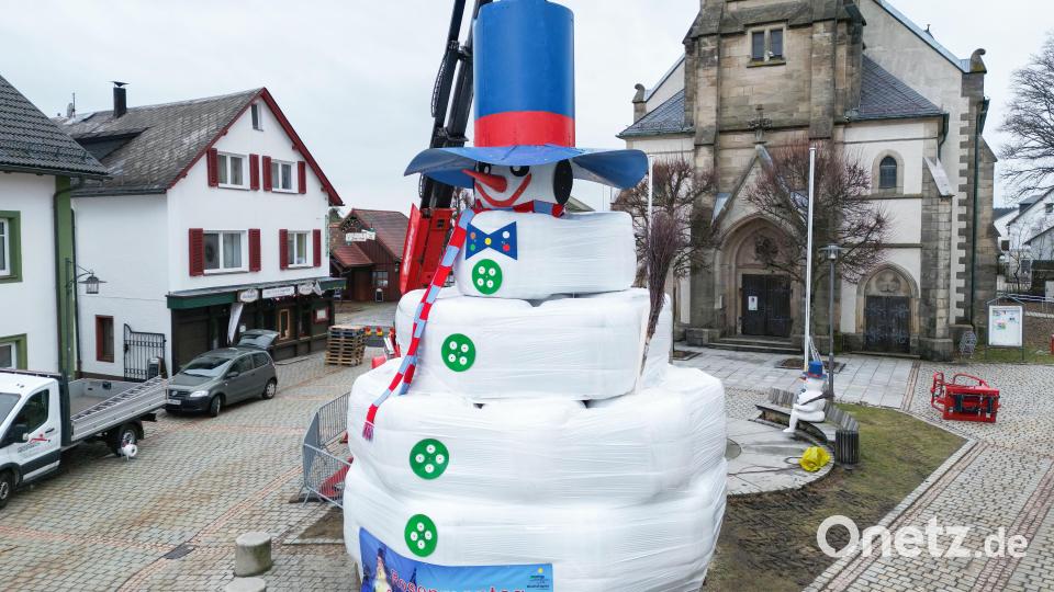 Der zwölf Meter hohe Schneemann «Jakob» steht für das Schneemannfest auf dem Marktplatz in Bischofsgrün. Wegen Schneemangels verwendeten die freiwilligen Helfer dieses Mal weiße Heuballen. Bild: Daniel Löb/dpa