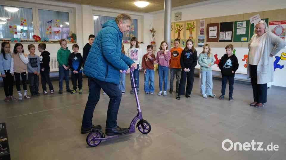 Der Vorsitzende der Verkehrswacht Vohenstrauß, Hans Messer, zeigt den Schülern die Nutzung der neuen Roller. Bild: fvo