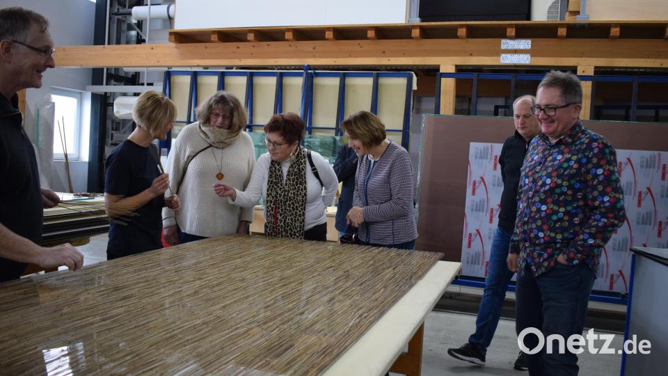 Eine Mitarbeiterin erläutert den Besuchern der SPD ihren Arbeitsschritt. Vor dem Erhitzen und Pressen gestaltet sie die Platte mit Bambuszweigen. Bild: szl