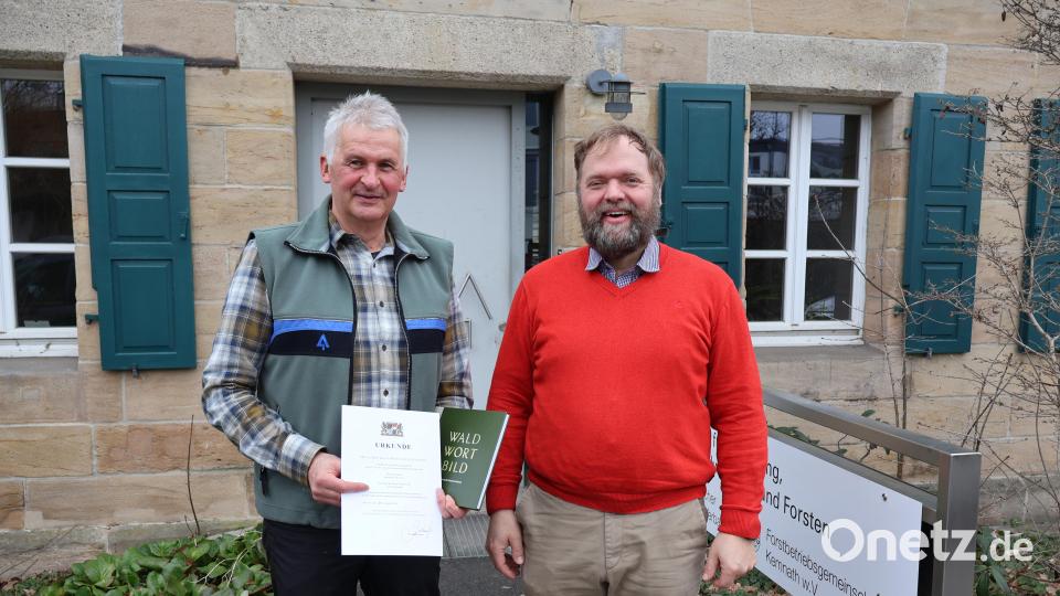 Karl-Heinz Melzer (links) erhält vom Bereichsleiter Forst, Christoph Hübner, die offizielle Urkunde zum Ruhestand und ein Abschiedsgeschenk – natürlich zum Thema „Wald“. Bild: Judith Zeitler/AELF/exb