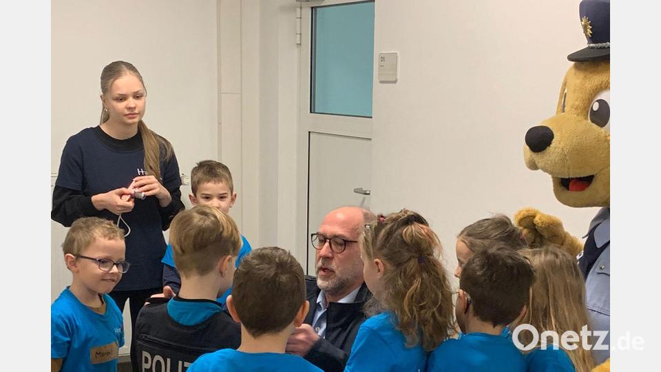 Polizeihauptkommissar Josef Prill &quot;behängt&quot; ein Kindergartenkind mit der schweren schusssicheren Weste. &quot;Toni, der Bär&quot;, das Präventionsmaskottchen,assistiert. Bild: Bundespolizei/exb