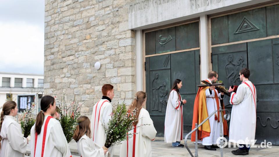 Nach der Prozession von der Mariä-Hmmelfahrtskirche zur Friedenskirche pocht Pfarrer Daniel Fenk am Palmsonntag mit dem Kreuz an die Kirchentüre und bittet um Einlass. Bild: rgr