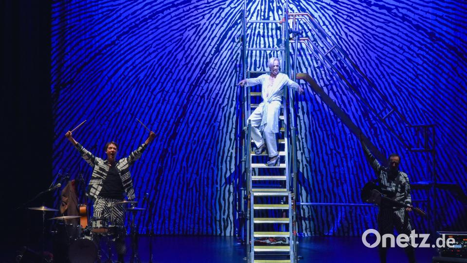Hier steigt David Bowie (Hans Piesbergen) von seinem Asteroiden 342843 herab ins Stadttheater in Amberg. Die Stufe ist steil, die Heels sind high. Links neben ihm Schlagzeuger, Gitarrist und vielseitiger Darsteller Sebastian Strehler, rechts davon Gitarrist und Multifunktionsschauspieler Michael Schönmetzer. Bild: Stephan Huber