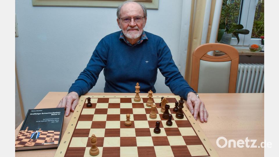 Heinz Däubler am Brett mit einem Schachproblem, das er zum 100-jährigen Bestehen des Schachclubs Furth im Wald 2022 komponiert hat. Links sein neues Problemschach-Buch. Bild: Stephan Huber