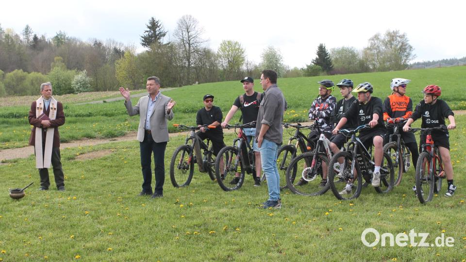 Bürgermeister Rainer Rewitzer (vorne, Mitte) freut sich wie Christopher Maschke (rechts daneben) über den Bikepark. Die Segnung nimmt Pater Thomas Mühlberger (links) vor. Bild: pi