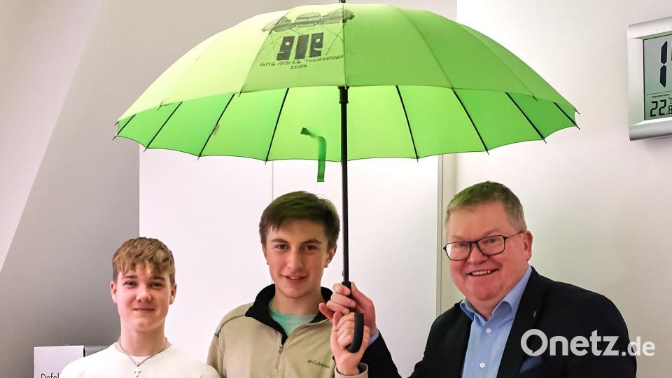Philipp Hummel und Lennart Kohl (von links) überreichten dem Schirmherrn Michael Cerny den passenden Schirm – mit eigens für die Theatertage entworfenem Logo. Bild: Peter Ringeisen