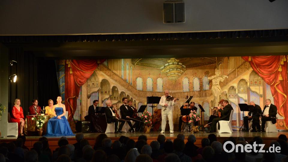 Orchesterchef Wenzel Plasil begeistert mit einem Violinsolo, die Interpreten hören von ihrem kleinen Tisch auf der Bühne (links) zu. Bild: bey