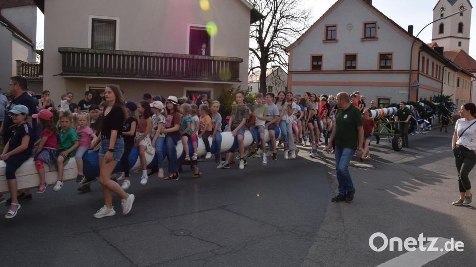 Der Maibaum wird zu seinem angestammten Platz gebracht. Traditionell dürfen sich die Kinder auf den letzten Metern auf den Baum setzen. Bild: fla